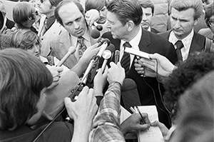 Photo of Ronald Reagan surrounded by reporters and microphones