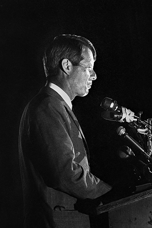 Photo of Robert Kennedy at podium with microphones, speaking
