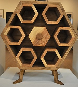 Woodworking shelving representing honeycomb-- center sexagon hand handle (maybe a drawer), Jordan Sobotka, Beekeep