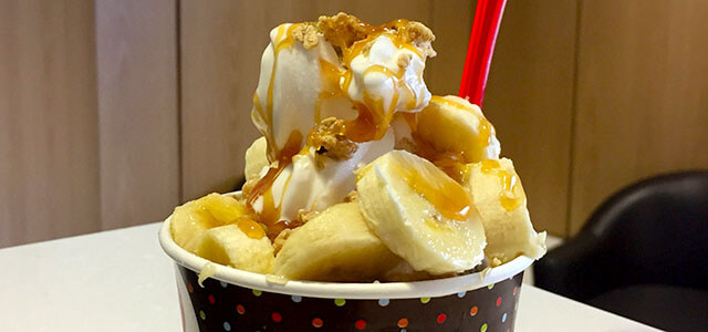 Yogurt in a cup covered in bananas, granola and caramel