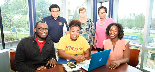 Several students and staff of the multicultural center, posing in front of a laptop