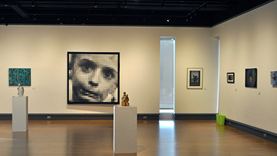 gallery shot with 2d and sculpture, large pixel based child photo visible in background