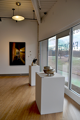 View of gallery with clay sculpture in foreground, 2d art in background