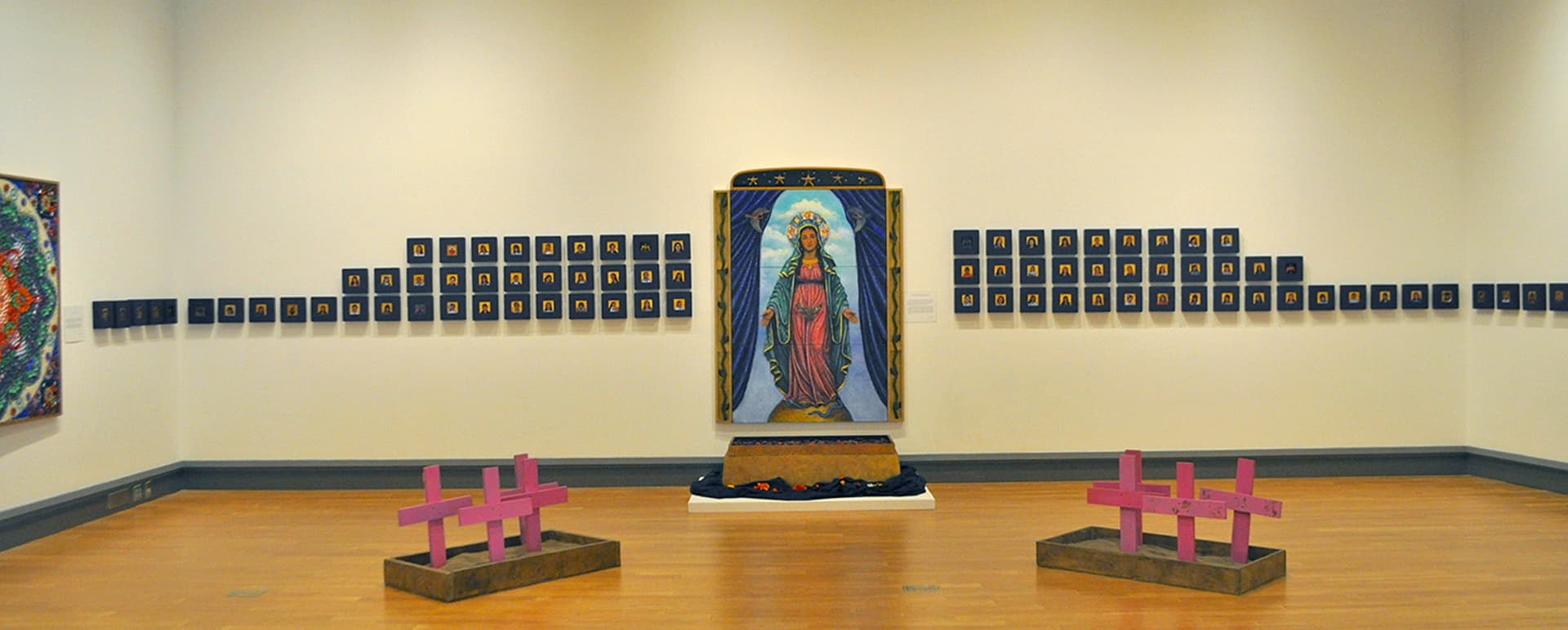 Installation view of Diane Kahlo’s Las Desaparecidas de Ciudad Juarez: Homage to the Missing and Murdered Girls of Juarez Mexico.  Image includes paintings, mixed media work, and sculptural pieces.