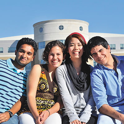 4 international students posing for a photo in front of the library