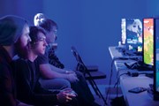 people playing video games on PCs in a dark room