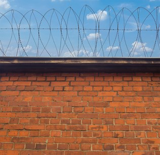 brick wall topped with barbed wire