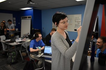 A student writes on a dry erase board during USI's TCA