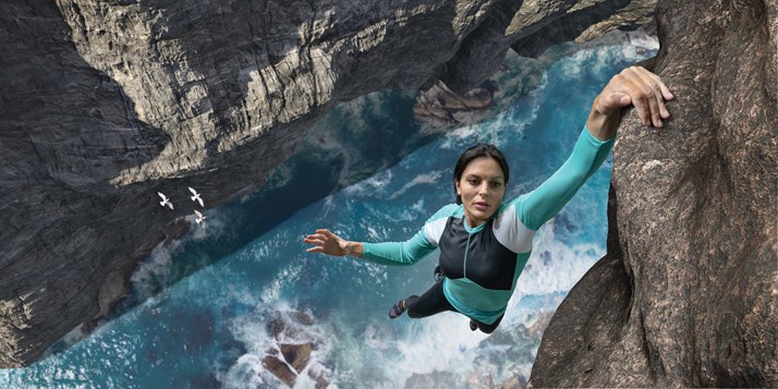 stock photo of a woman climbing a cliff over a river