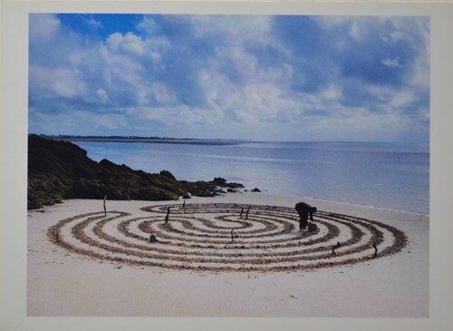 image of a labrynth made in the sand on a coastal beach