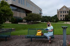 Student reading while sitting on a bench on the Quad