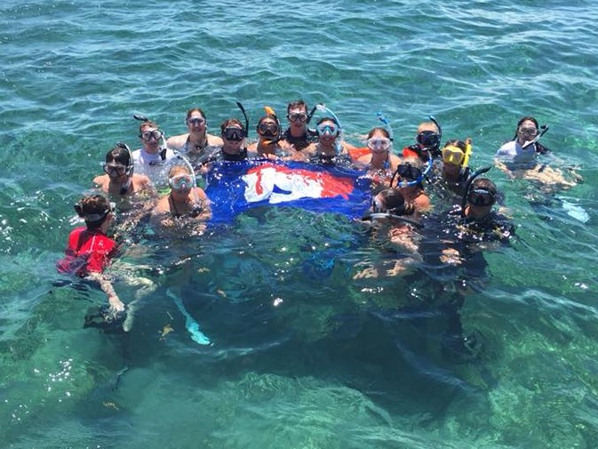 USI Biology Students with a USI flag in the ocean.